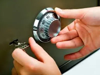 Primer plano de un cerrajero abiendo una caja fuerte.